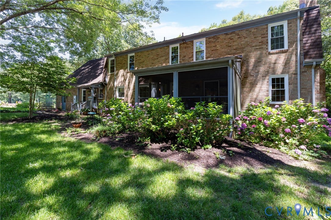Brick exterior with multiple windows, a screened porch, and established landscaping