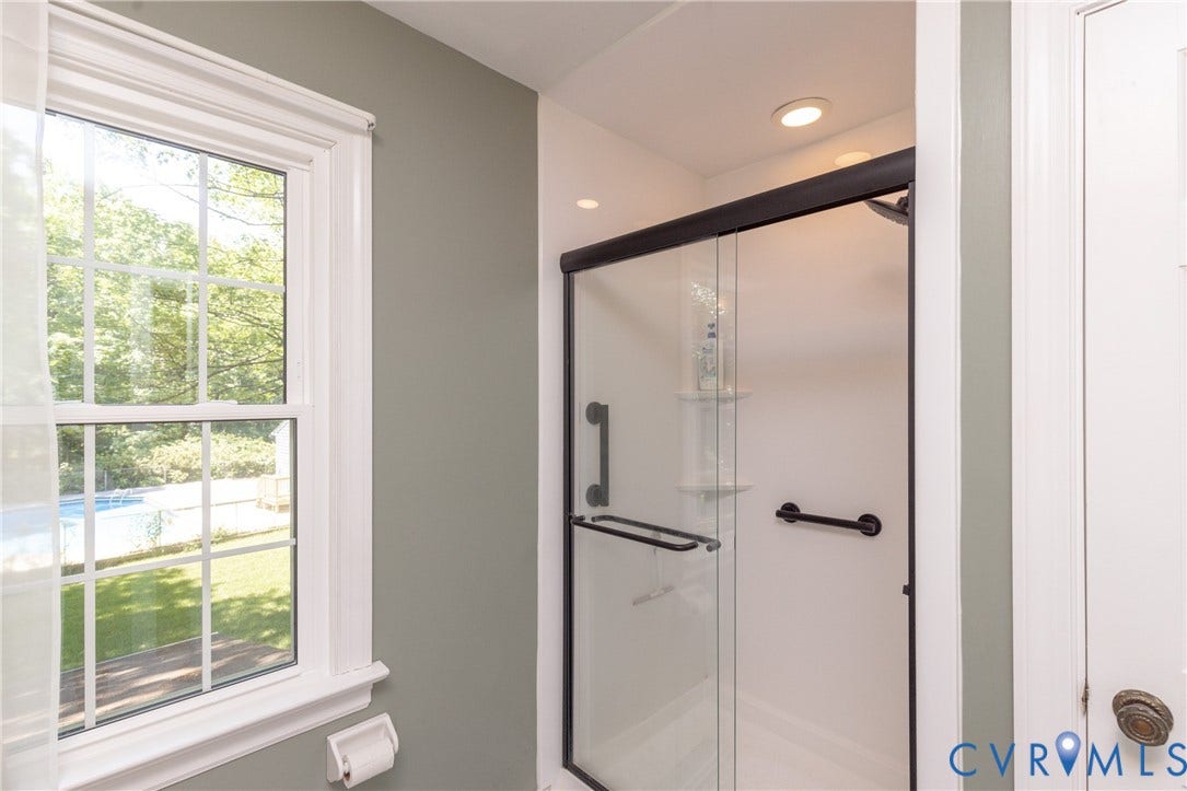 Shower with glass enclosure, recessed lighting, and matte black hardware