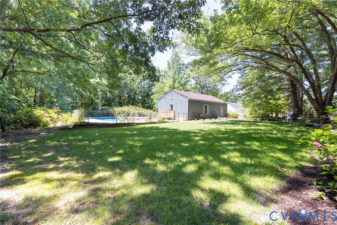 Expansive lawn area with mature trees, fenced in-ground pool, and detached structure