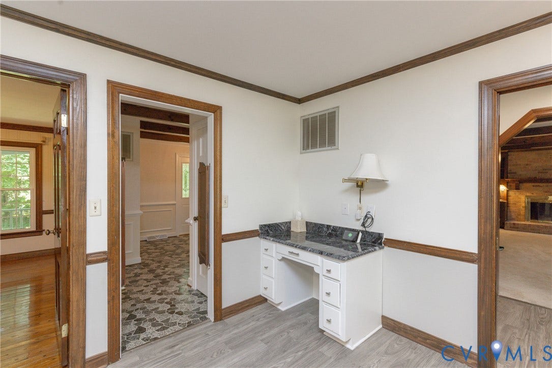 Built-in desk area with a dark stone countertop, white cabinetry, and a wall-mounted fixture