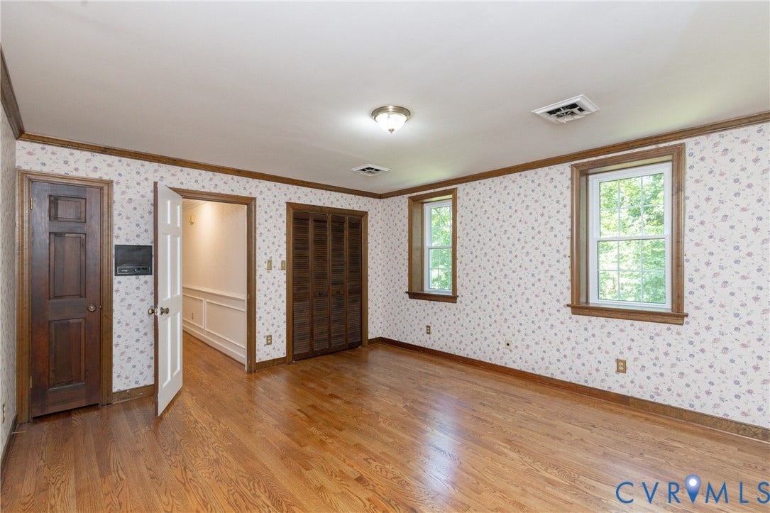 Hardwood flooring with wood trim accents, a bifold door closet, and two windows
