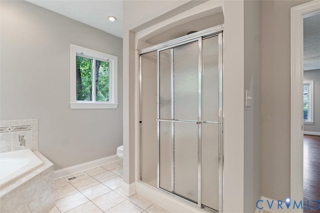 Recessed lighting illuminates the bathroom with a window and a glass-enclosed shower