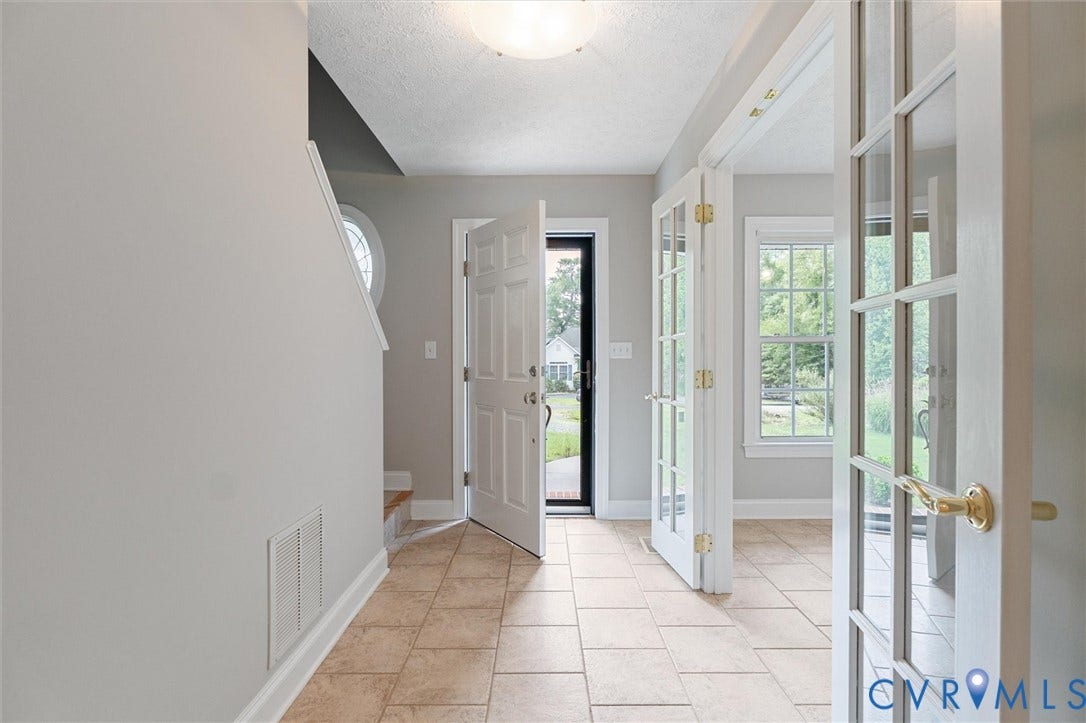 Tiled flooring, white paneled doors, dual French doors, window with grid panes, and a circular window