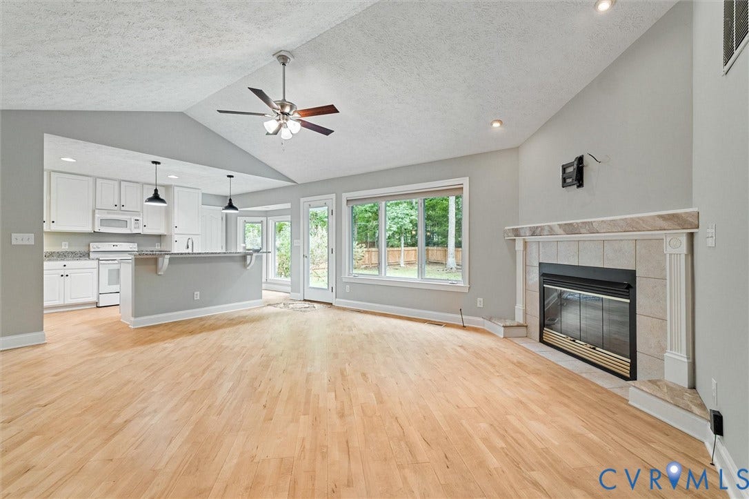 Vaulted ceilings, wood-finish flooring, and a fireplace with a tile surround