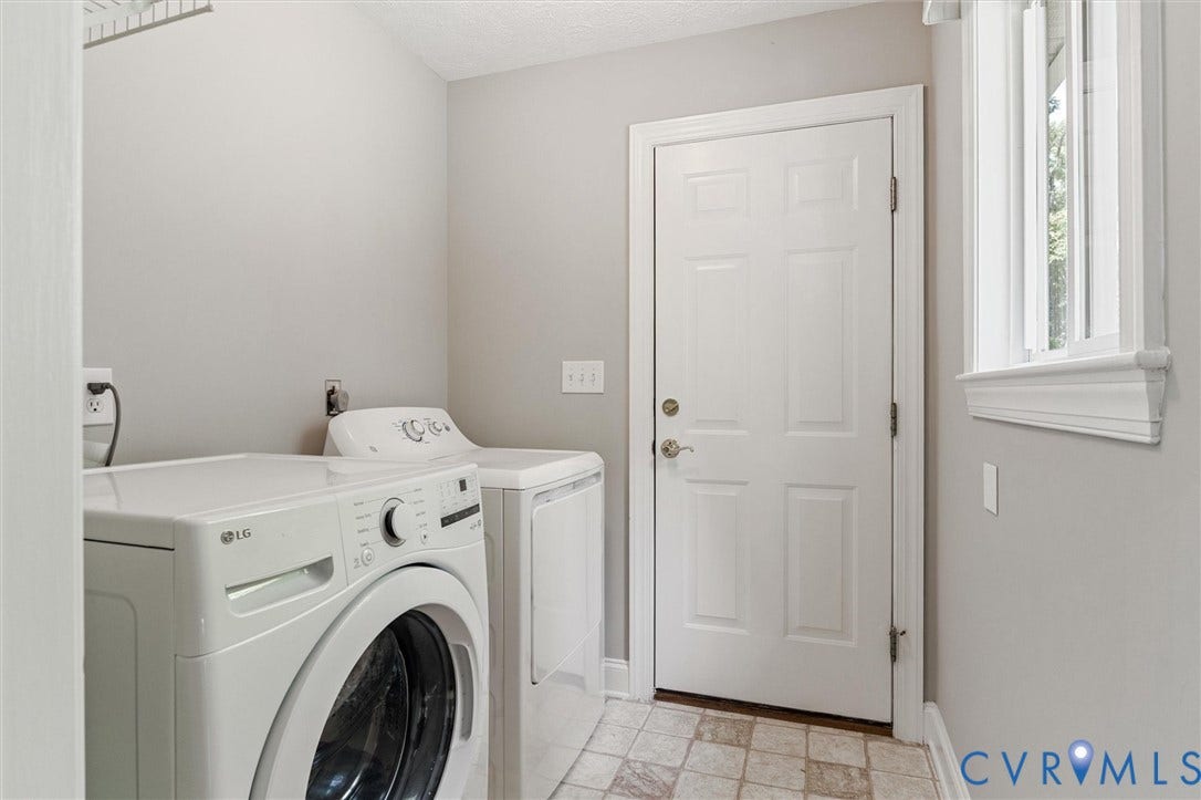 Dedicated laundry space with light-toned walls, a paneled door, and a window with white trim