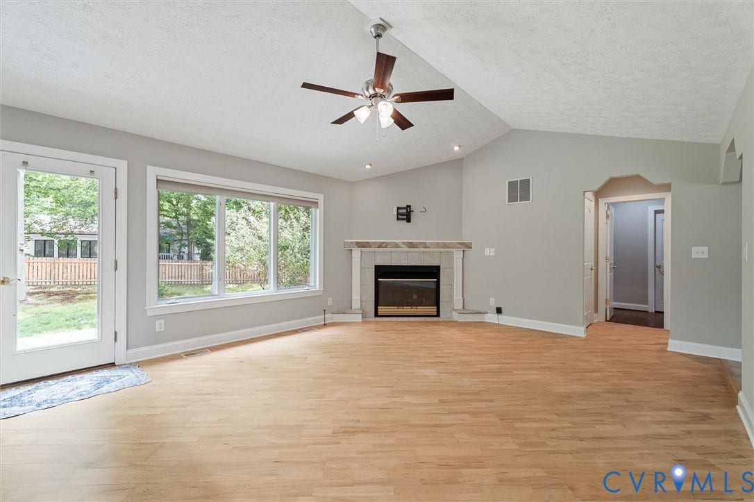 Hardwood flooring, vaulted ceiling, built-in fireplace, ceiling fan, and extensive windows