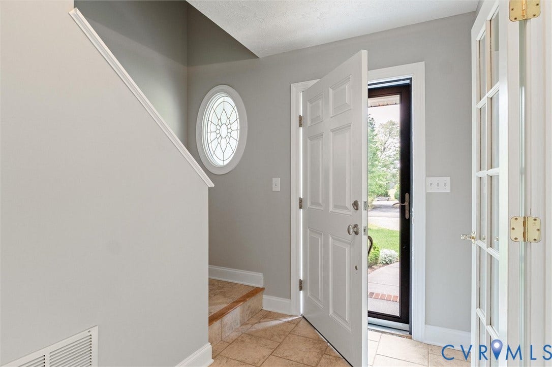 Foyer featuring tiled flooring, a decorative oval window, and a paneled entry door with side light