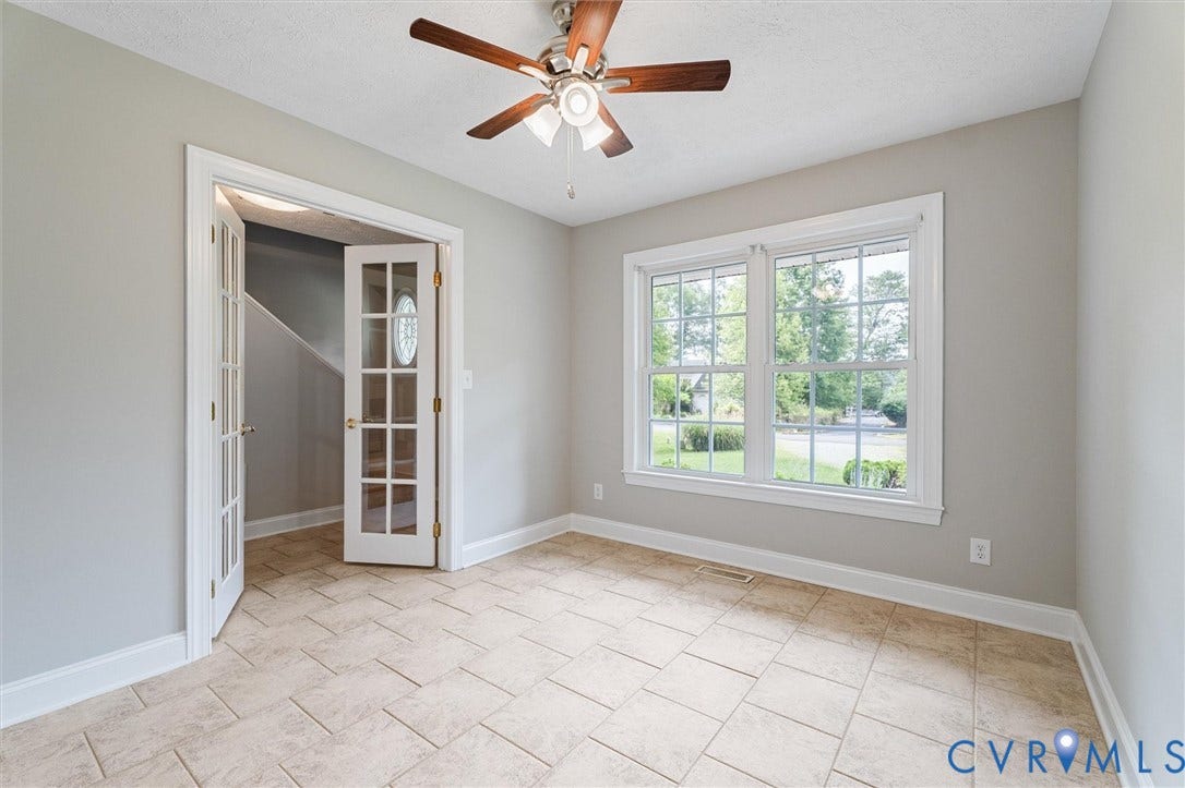 Neutral paint palette, two large windows, tile flooring, white trim, and a ceiling fan with light fixture
