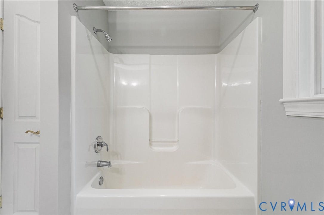 White acrylic tub and shower combination with chrome fixtures
