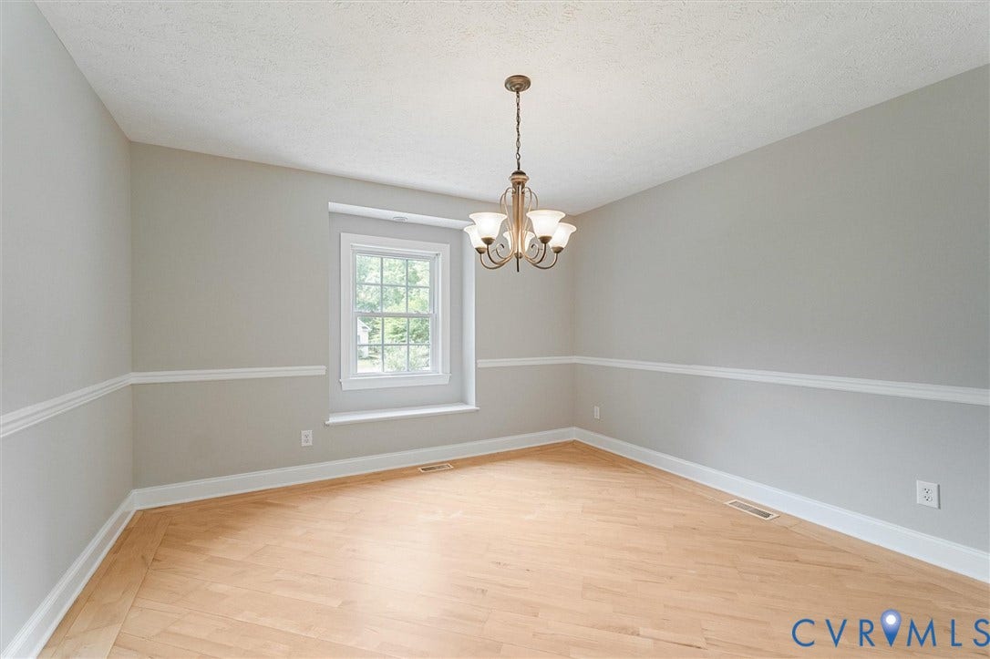 Room featuring wood-finish flooring, a decorative chandelier, and a large window