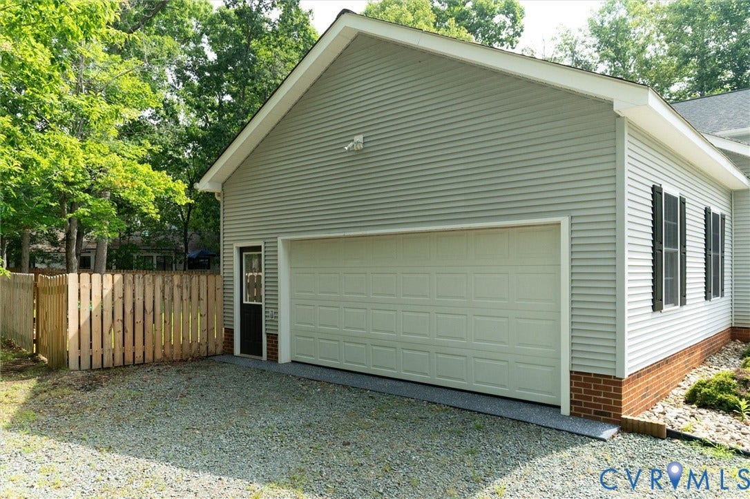 Attached garage with a panel door, light gray siding, and a brick foundation