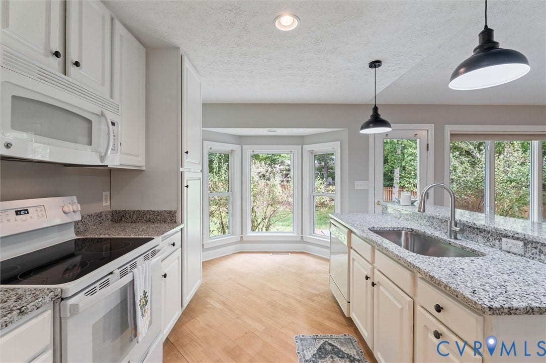 Kitchen featuring white cabinetry, granite countertops, stainless steel sink, and wood-finish flooring
