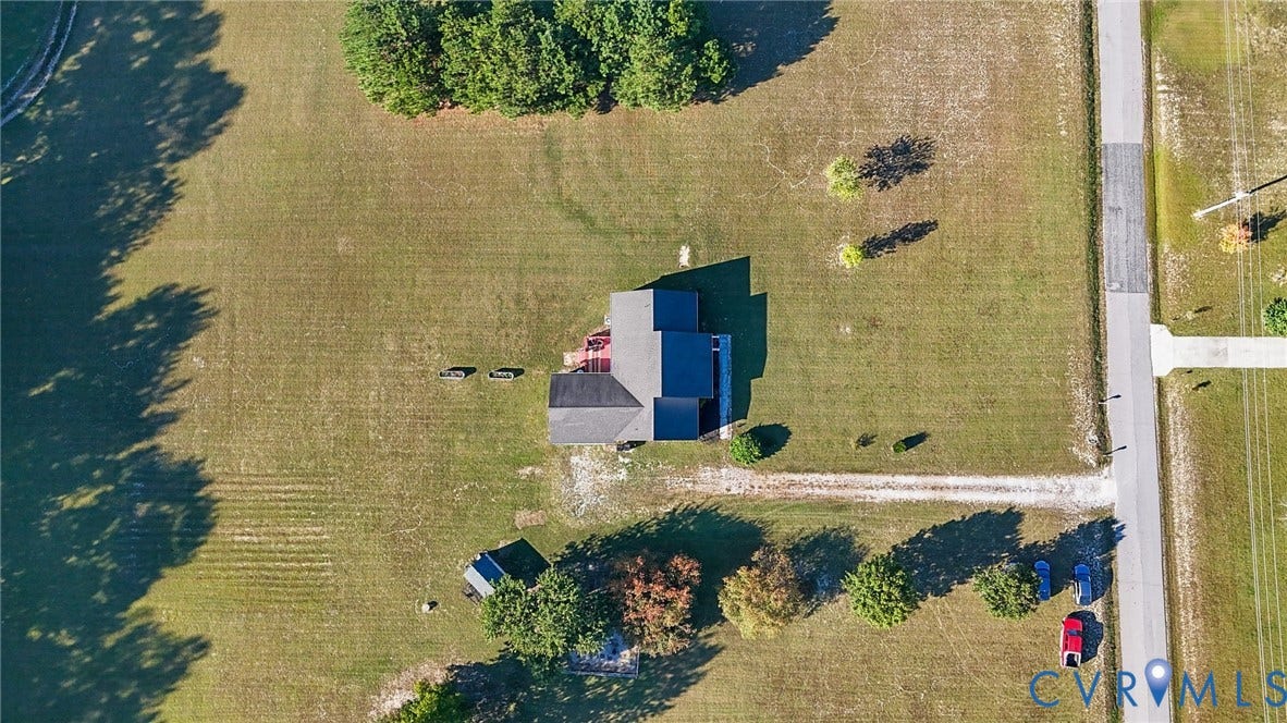 20550 Horseshoe Road, Prince George, VA 23830 Gravel driveway leading to a residential structure with a dark shingle roof, surrounded by expansive green space and mature trees