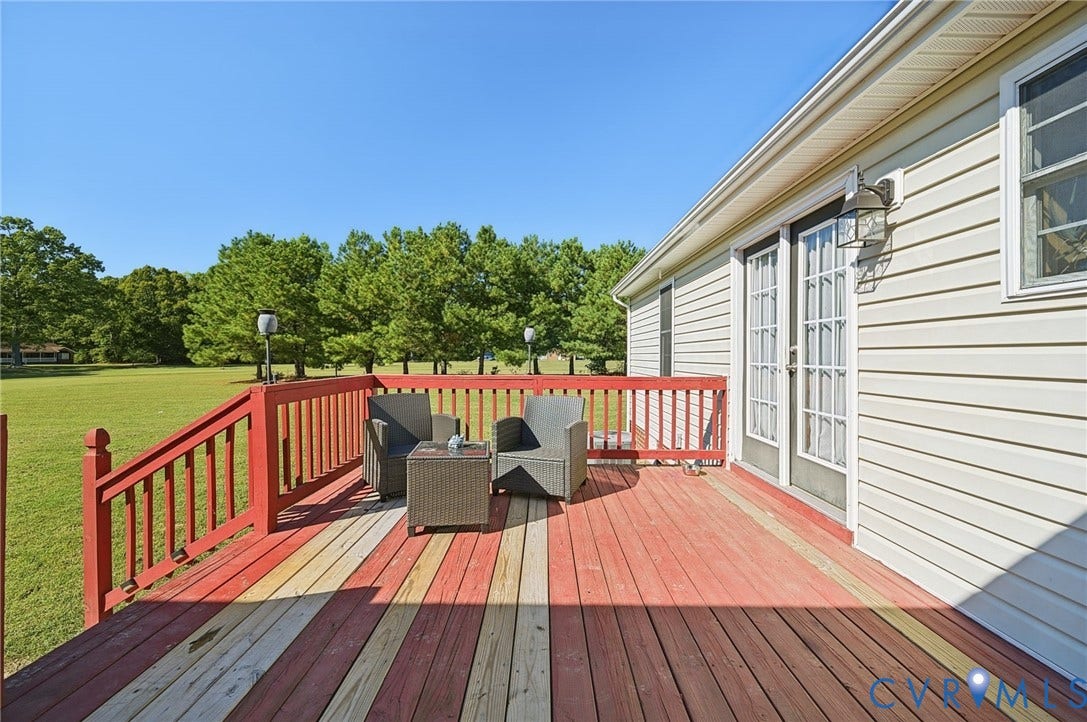 20550 Horseshoe Road, Prince George, VA 23830 Expansive wood-finish deck with red railings and painted striped planks, featuring a double glass panel door and exterior wall sconce, overlooking a large grassy area with mature trees