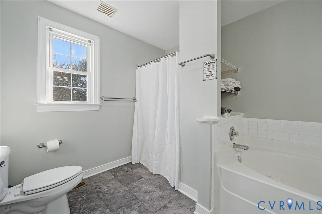 20550 Horseshoe Road, Prince George, VA 23830 Window with white trim, deep soaking tub, gray tile flooring, built-in shelving, and white shower curtain