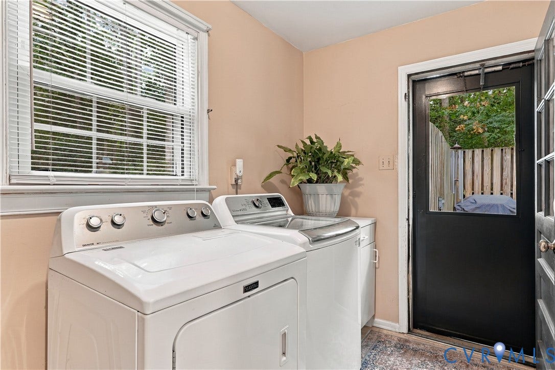 Functional laundry area with a window, base cabinetry, and a door providing exterior access