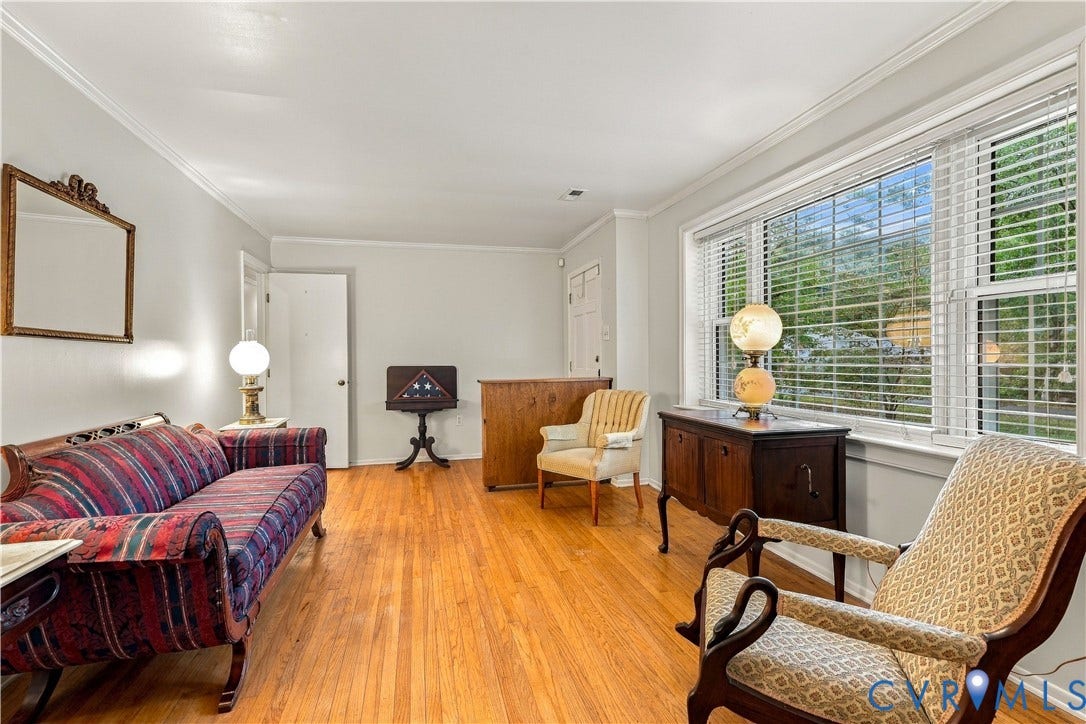 Hardwood flooring, white crown molding, white baseboards, and a large window with blinds