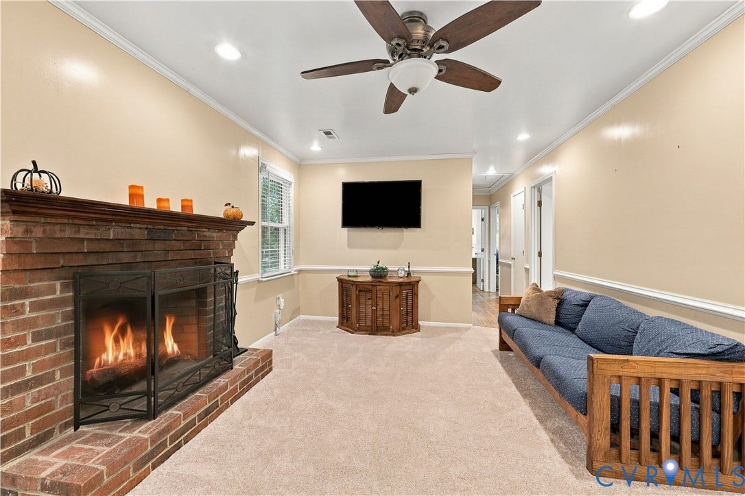 Brick fireplace with a metal screen, recessed lighting, ceiling fan, and carpet flooring