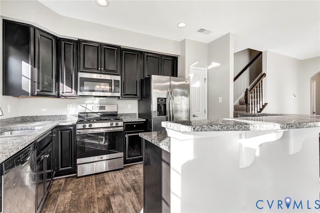 8926 Ringview Drive, Mechanicsville, VA 23116 Kitchen featuring dark wood cabinetry, light-toned countertops, stainless steel appliances, and wood-finish flooring