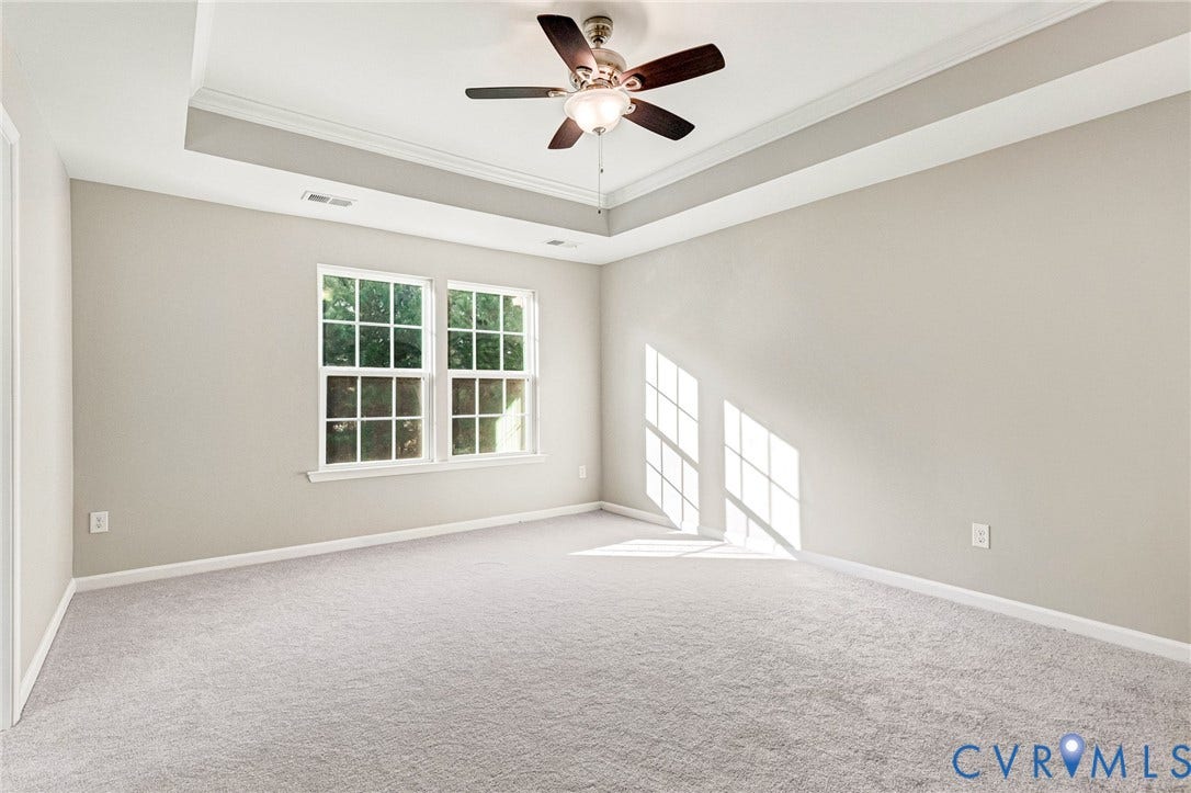 8926 Ringview Drive, Mechanicsville, VA 23116 Tray ceiling with crown molding, ceiling fan, two windows with grids, light gray walls, and light gray carpeting