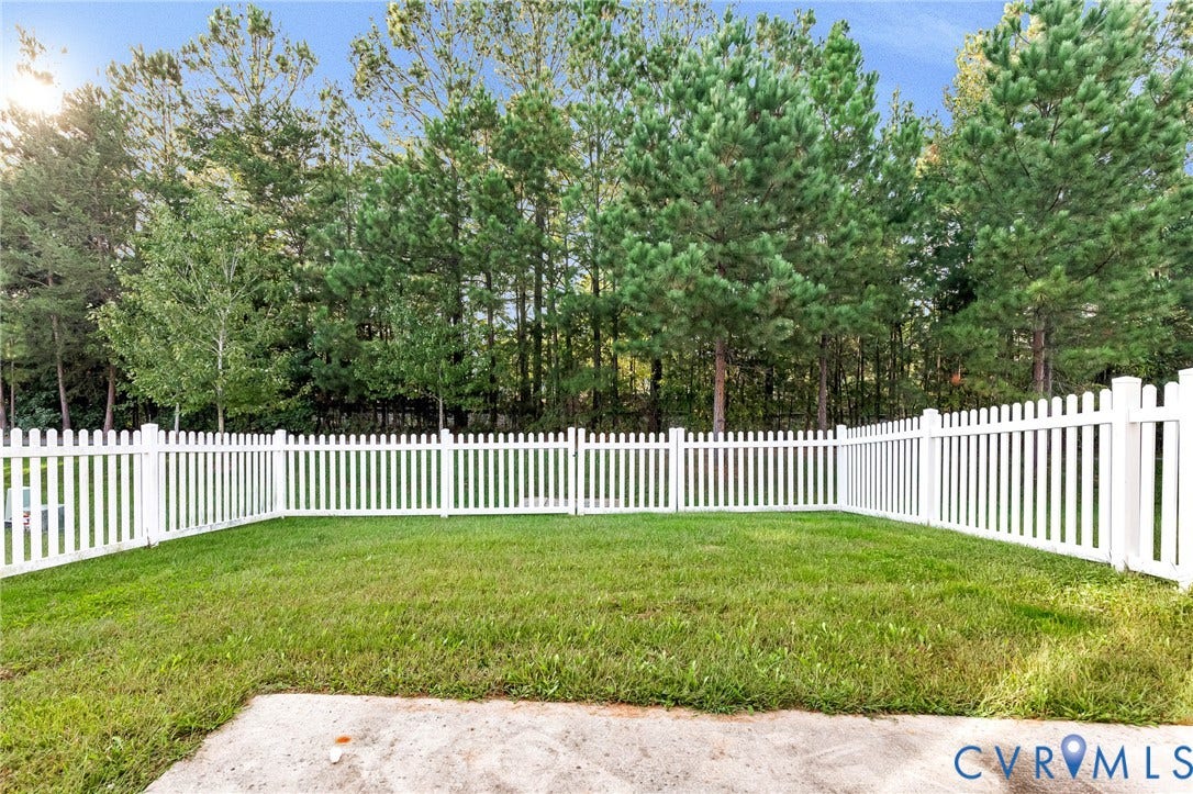 8926 Ringview Drive, Mechanicsville, VA 23116 Expansive backyard featuring a white picket fence, a lush lawn, and mature trees providing a natural backdrop
