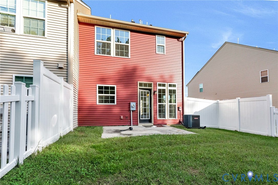 8926 Ringview Drive, Mechanicsville, VA 23116 Red horizontal siding exterior with a concrete patio, white vinyl fencing, and a grassy yard
