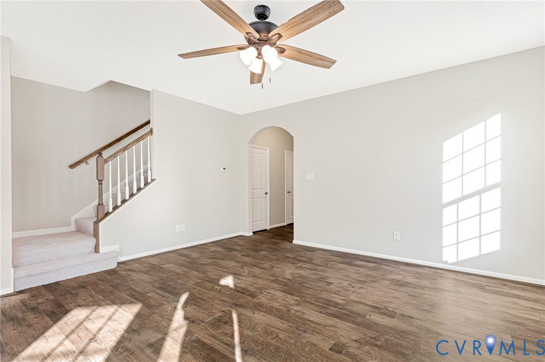 8926 Ringview Drive, Mechanicsville, VA 23116 Wood-finish flooring, staircase with carpeted treads and wood handrail, ceiling fan with light fixture, arched doorway, and window