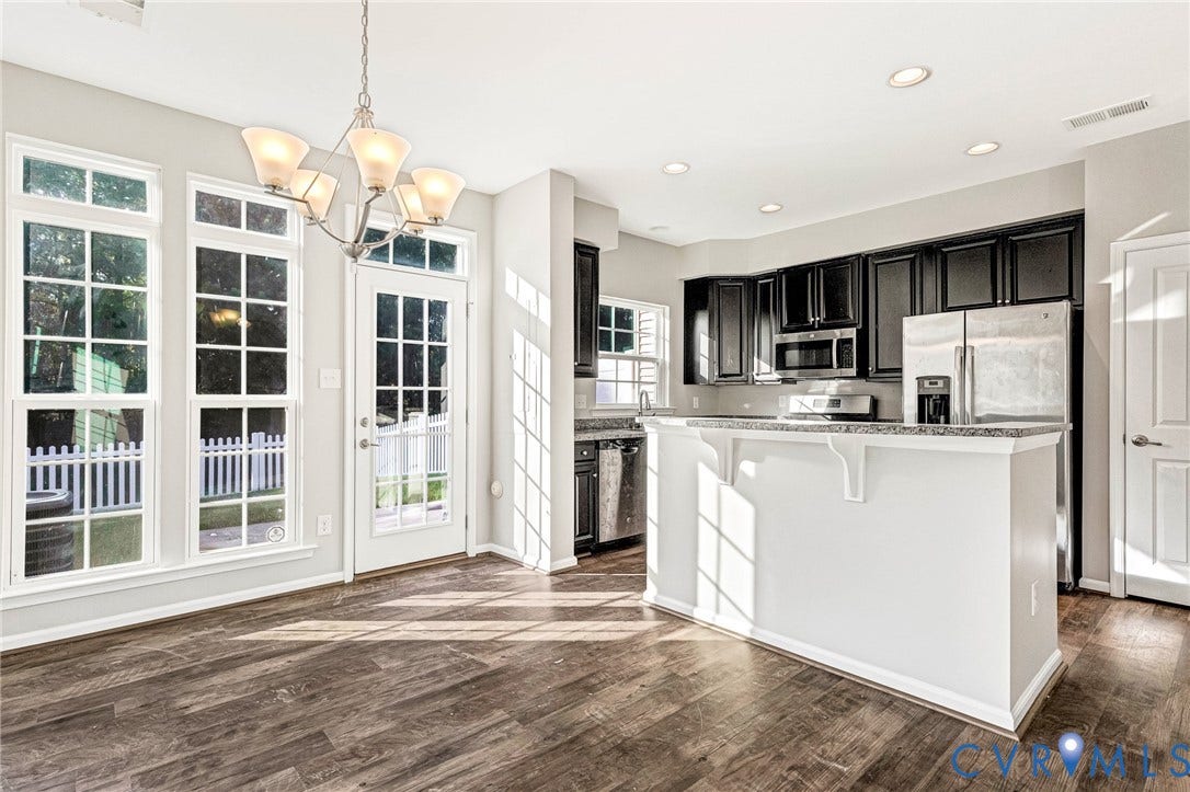 8926 Ringview Drive, Mechanicsville, VA 23116 Wood-finish flooring, white paneled door, three large windows, white kitchen island with counter seating, stainless steel appliances