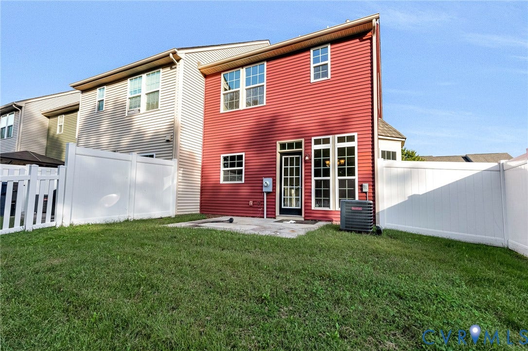 8926 Ringview Drive, Mechanicsville, VA 23116 Red siding exterior, white vinyl fencing, grass lawn, concrete patio, and large white-framed windows