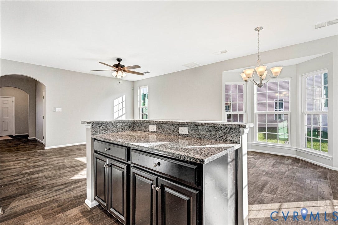 8926 Ringview Drive, Mechanicsville, VA 23116 Granite-finish countertop with dark wood cabinetry, wood-finish flooring, bay window, and a decorative chandelier