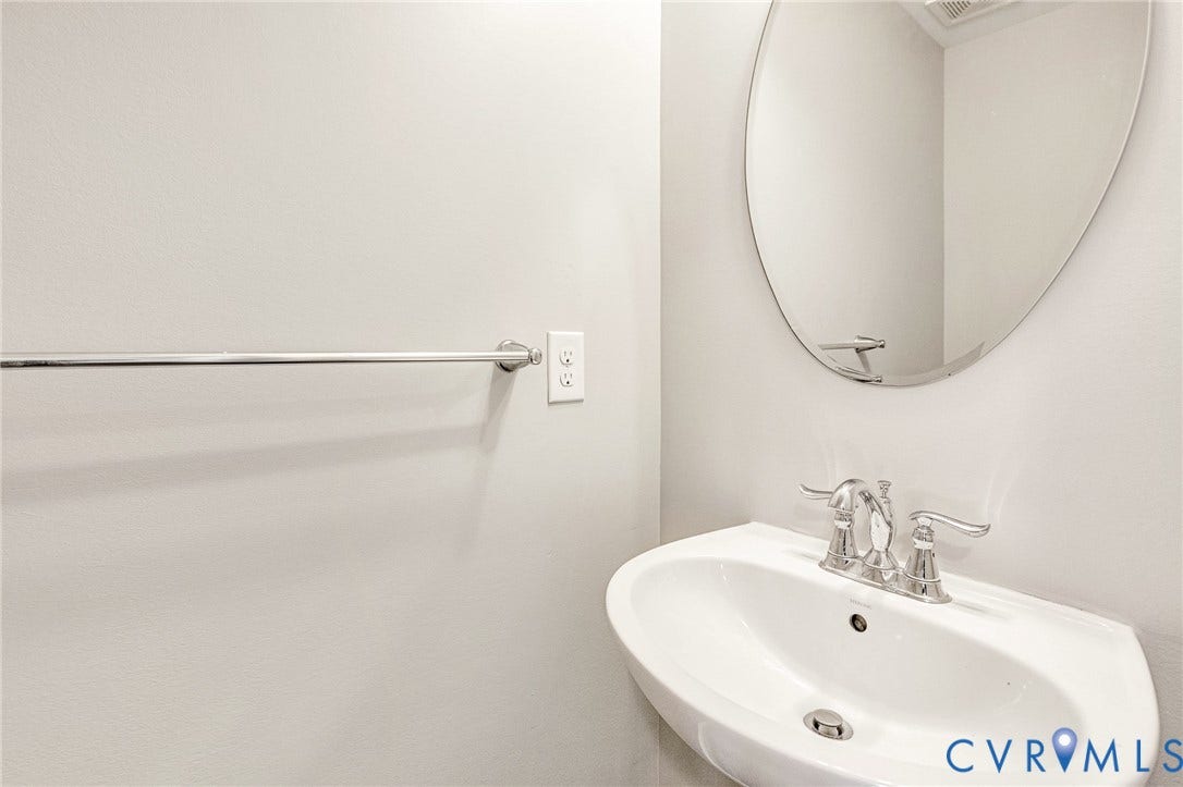 8926 Ringview Drive, Mechanicsville, VA 23116 Wall-mounted sink with chrome faucet, an oval mirror, and a chrome towel bar