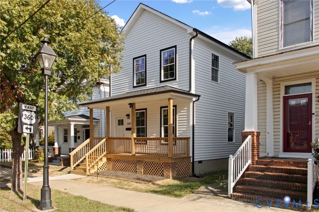 White siding exterior with black trim windows, covered front porch, and natural wood railings