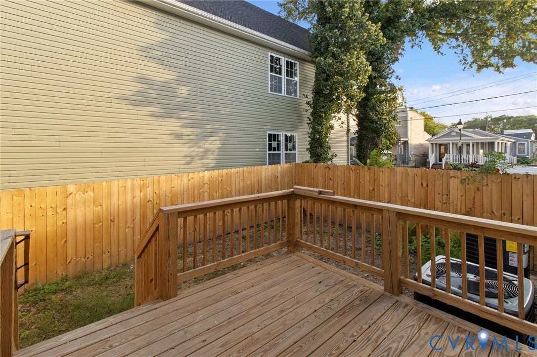 Wood deck with wood railings, wood privacy fence, and horizontal siding on the building