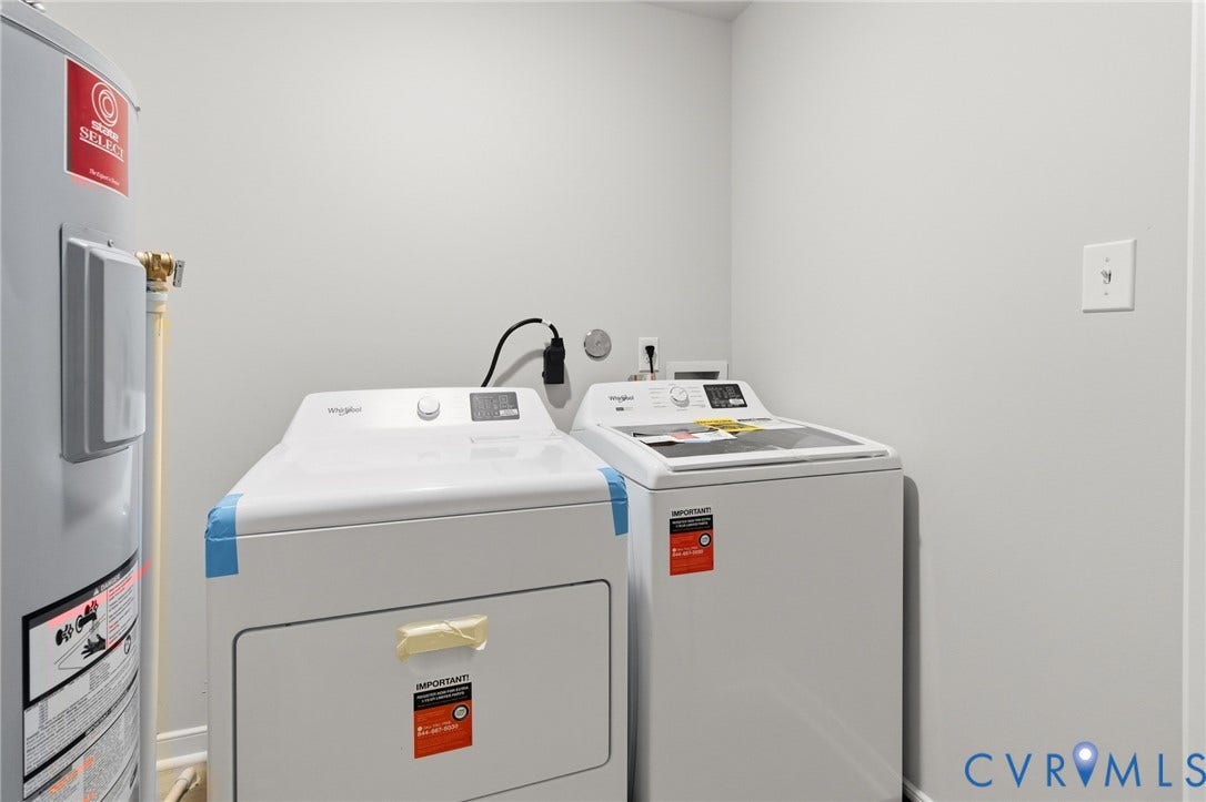 White washer and dryer appliances, water heater, and light gray wall paint