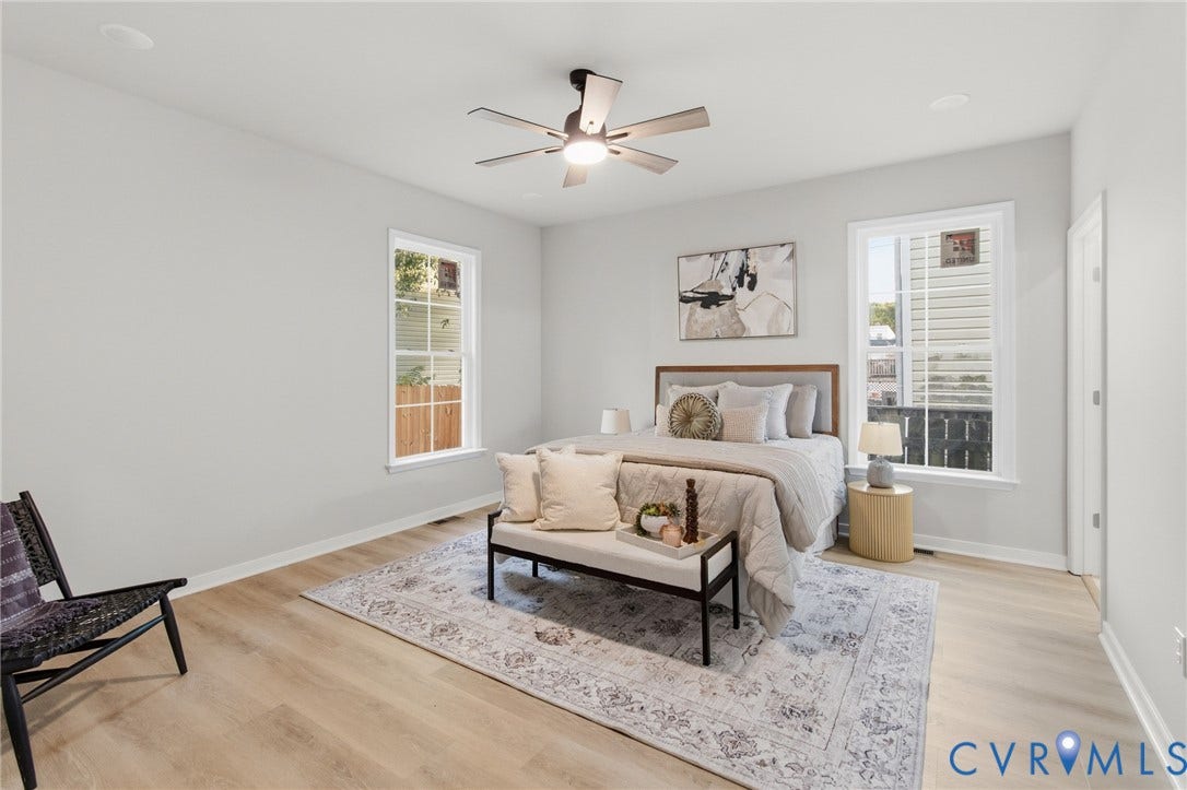 Recessed lighting, light wood-finish flooring, two large windows, ceiling fan with integrated lighting, and white trim throughout