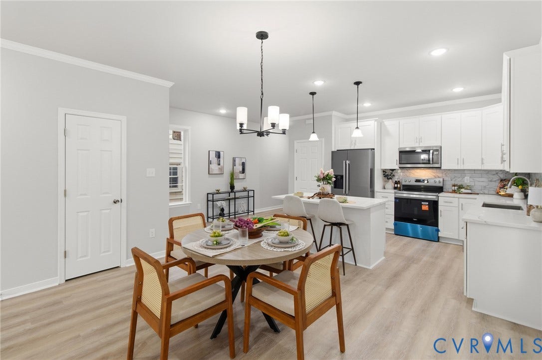 Open-concept kitchen and dining area featuring light wood-finish flooring, white cabinetry, a central island with bar seating, pendant lighting, and recessed lighting