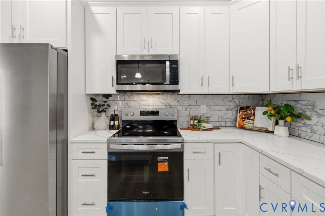 White shaker-style cabinetry, stainless steel appliances, quartz countertops, subway tile backsplash, and under-cabinet lighting