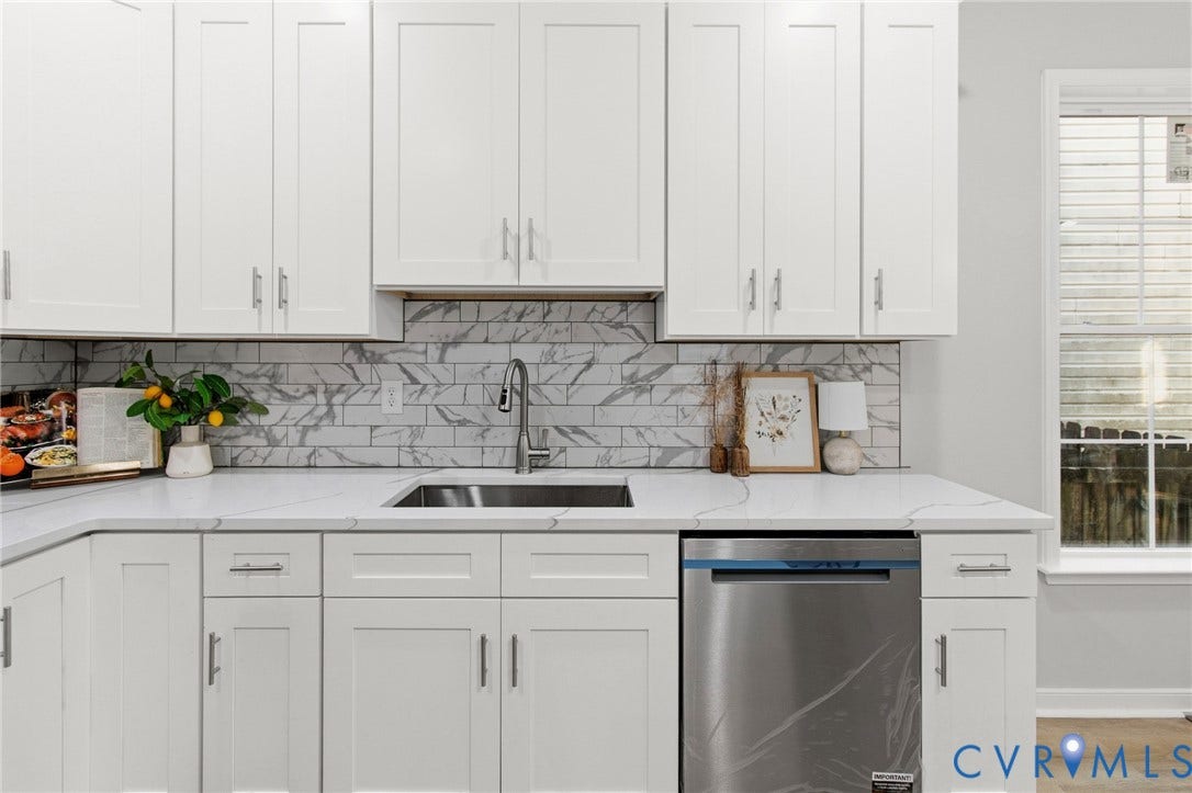 White shaker cabinetry, stainless steel dishwasher, undermount sink, quartz countertops, and a subway tile backsplash
