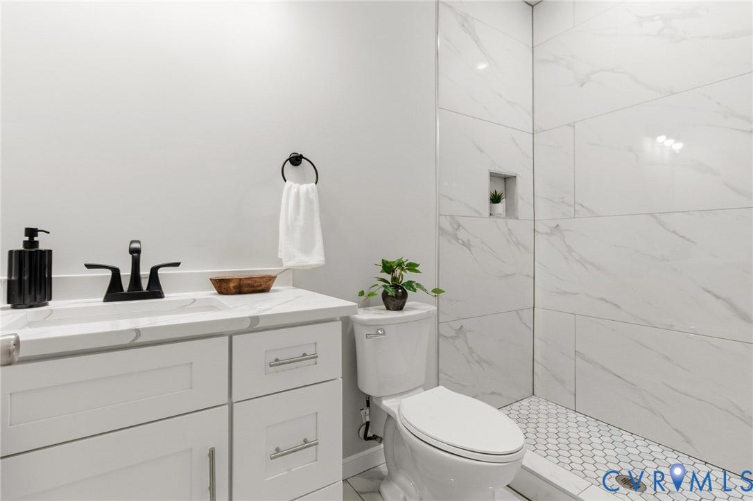 White vanity with shaker-style cabinetry, a white countertop, and a black-finish faucet