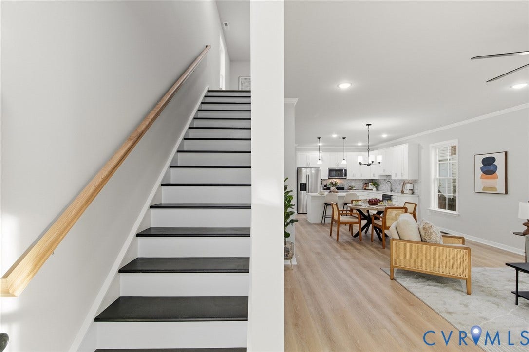 Open-concept living area with wood-finish flooring, recessed lighting, and a modern kitchen featuring white cabinetry, a kitchen island, and stainless steel appliances