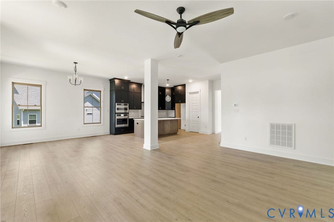 9514 Angels Share Drive, New Kent, VA 23141 Expansive open concept living space featuring wood-finish flooring, a modern ceiling fan, recessed lighting, and a kitchen with dark cabinetry and stainless steel double ovens