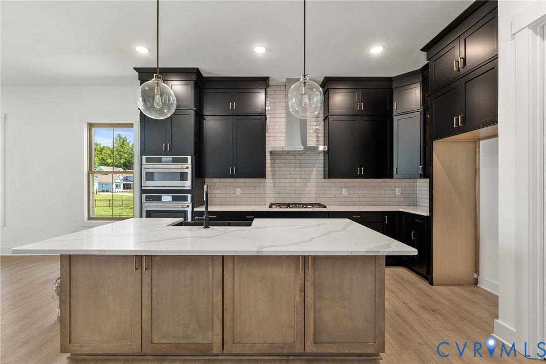 9514 Angels Share Drive, New Kent, VA 23141 Kitchen featuring black cabinetry, light wood-finish flooring, a central island with a light-toned countertop, and a subway tile backsplash