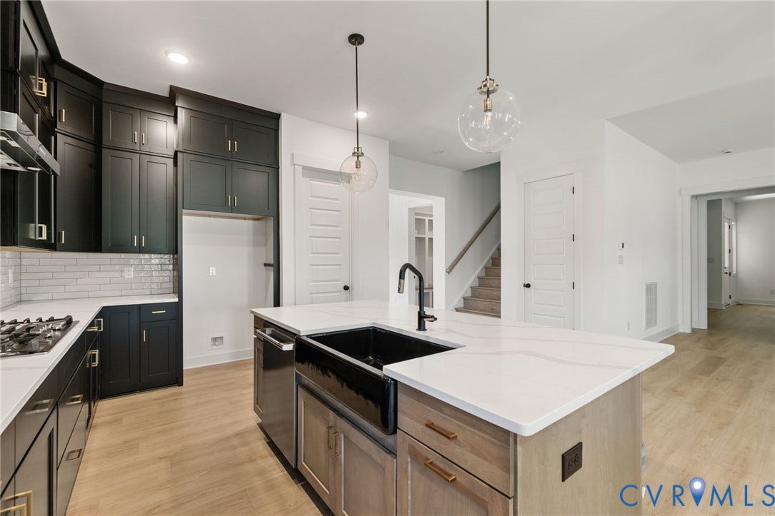 9514 Angels Share Drive, New Kent, VA 23141 Contemporary kitchen featuring dark cabinetry, white countertops, a large center island with an integrated sink, and wood-finish flooring