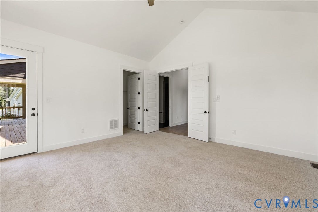 9514 Angels Share Drive, New Kent, VA 23141 Vaulted ceiling room with light carpet flooring and a glass-paneled door opening to a wooden deck