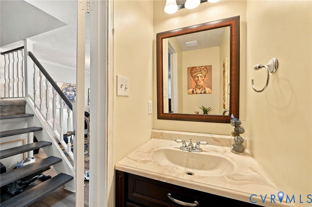 8434 Shannon Green Court, Henrico, VA 23228 Corner vanity with integrated sink, wood-finish cabinetry, and chrome faucet