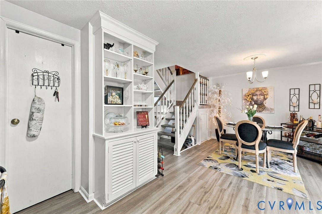 8434 Shannon Green Court, Henrico, VA 23228 Built-in shelving unit with lower louvered cabinet doors, wood-finish flooring, staircase with white risers and wood treads, and a dining area with a brass chandelier