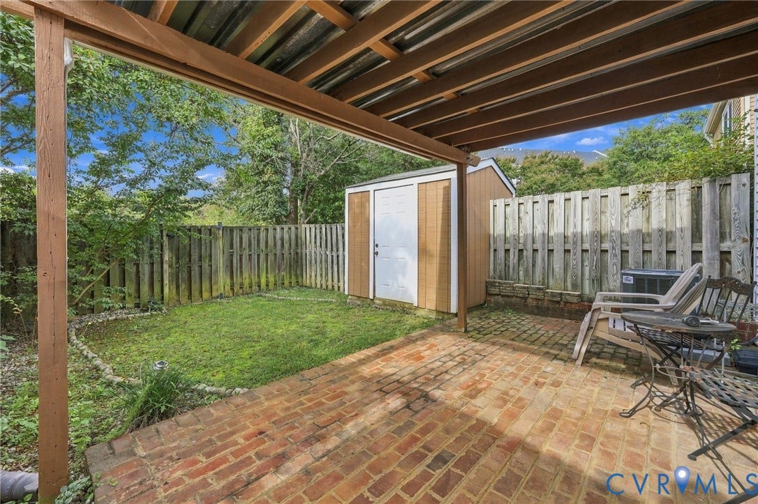 8434 Shannon Green Court, Henrico, VA 23228 Covered patio with brick pavers, wood privacy fencing, a storage shed, and a compact lawn