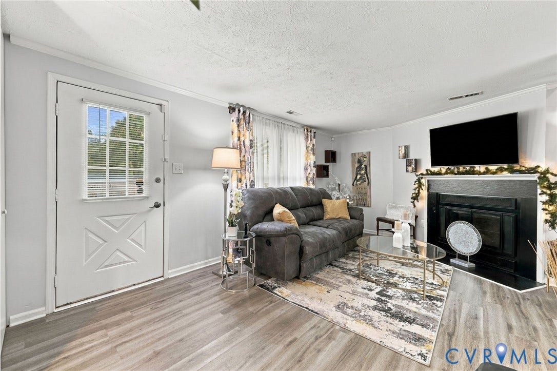 8434 Shannon Green Court, Henrico, VA 23228 Wood-finish flooring, white walls, and a fireplace with a dark surround