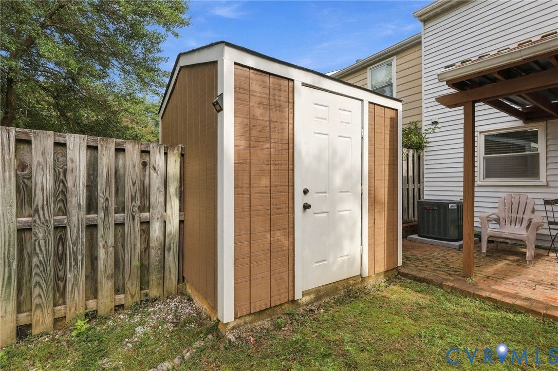 8434 Shannon Green Court, Henrico, VA 23228 Brown-paneled storage shed with white trim and a white door, positioned on a grassy lawn