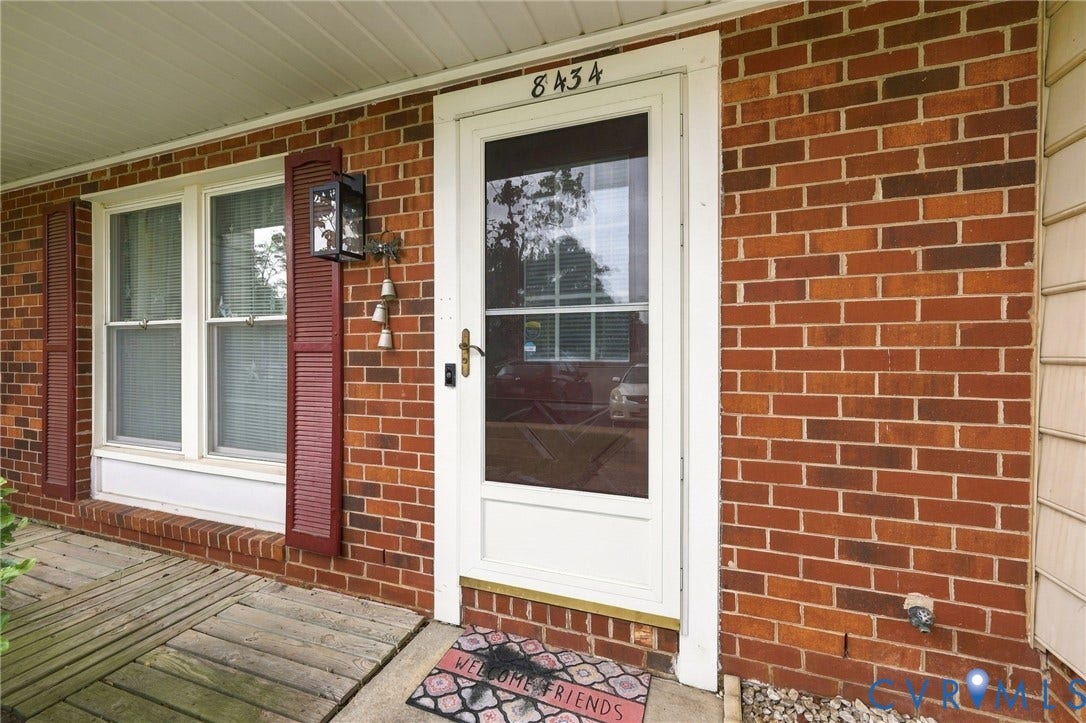 8434 Shannon Green Court, Henrico, VA 23228 Brick exterior detailing a white storm door, double-hung windows, and decorative shutters